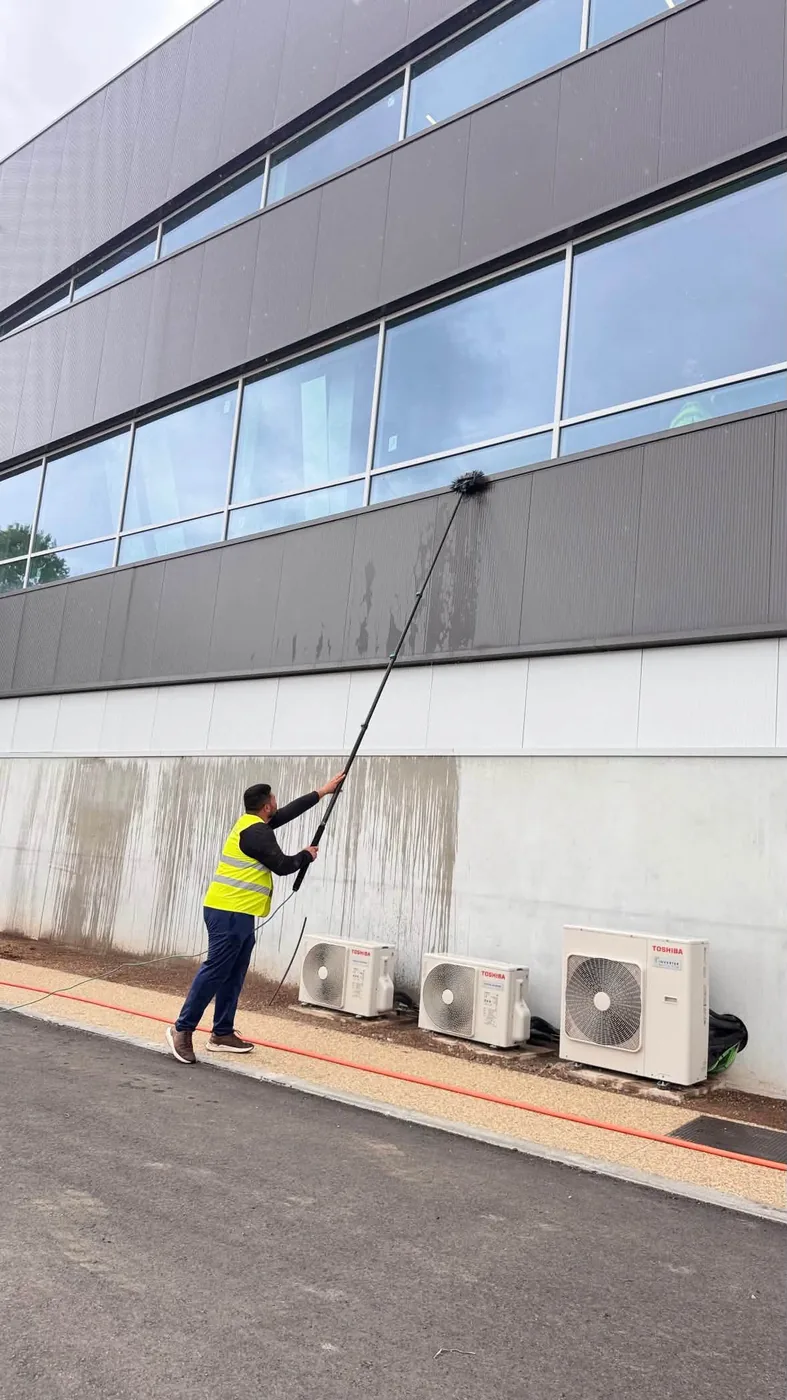 Profissional a limpar a fachada de um edifício de escritórios com pértiga telescópica