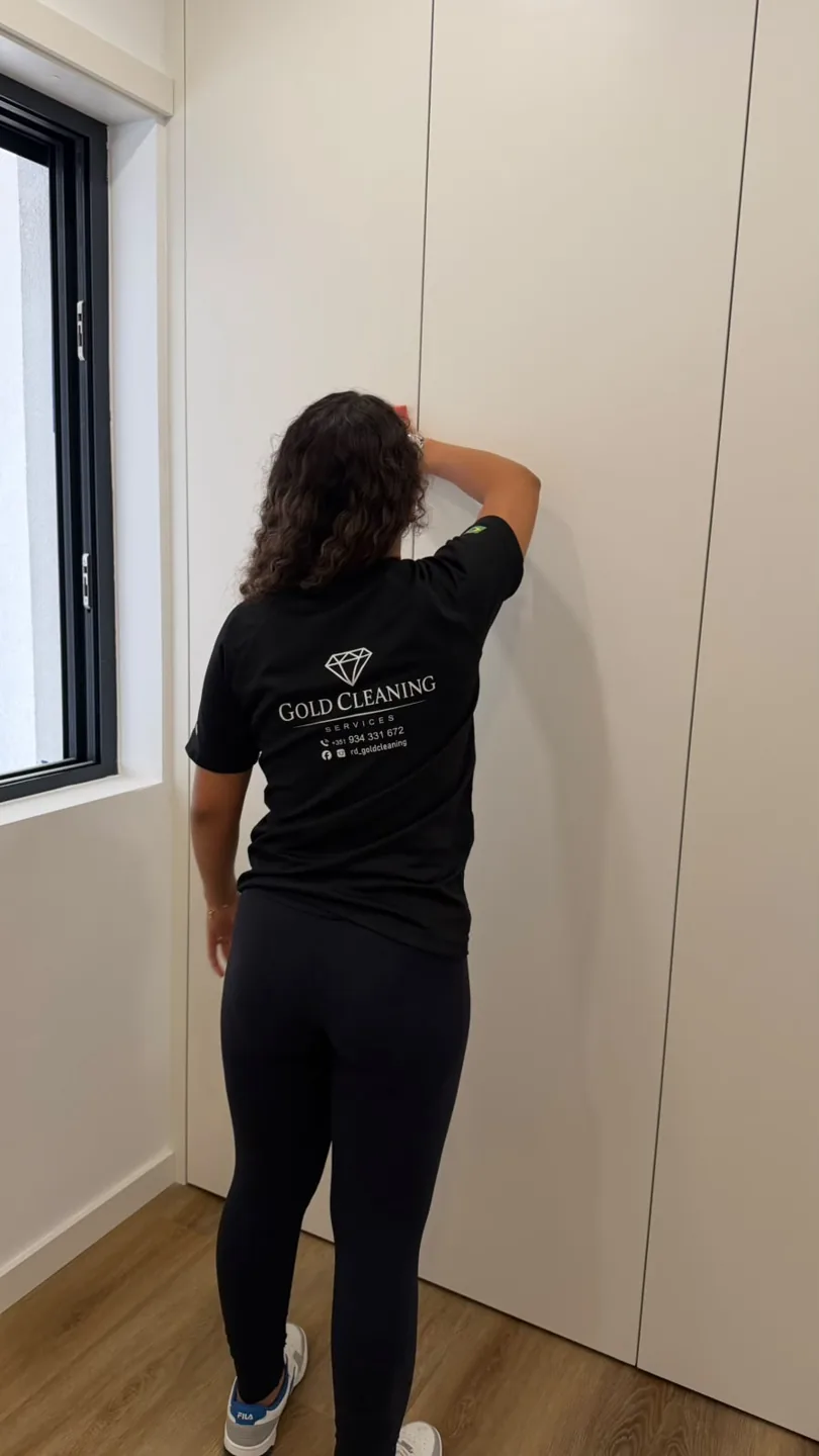 Profissional da Gold Cleaning, com t-shirt da marca, a limpar uma superfície interior