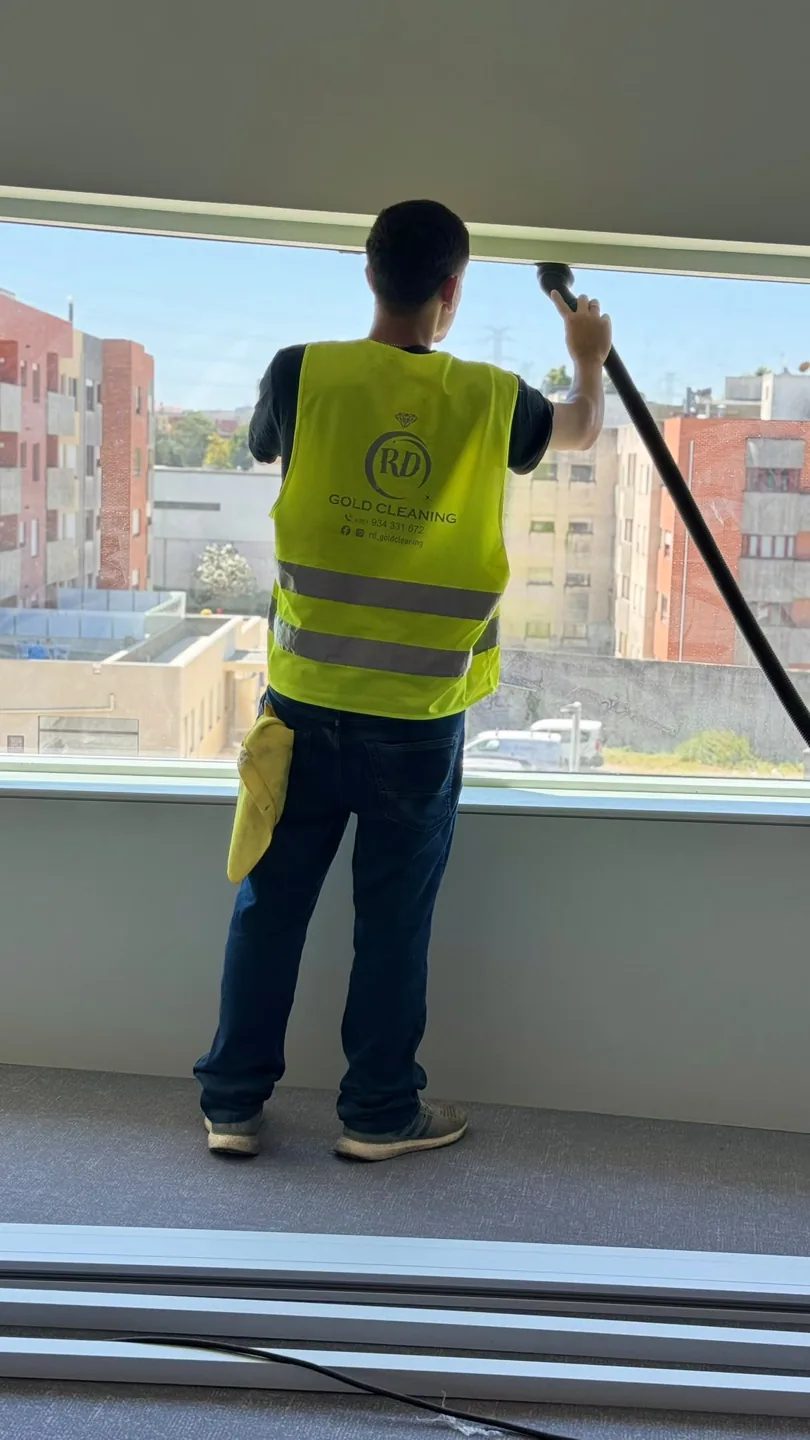 Profissional da Gold Cleaning, com colete da marca, a lavar um vão de vidro de grande dimensão