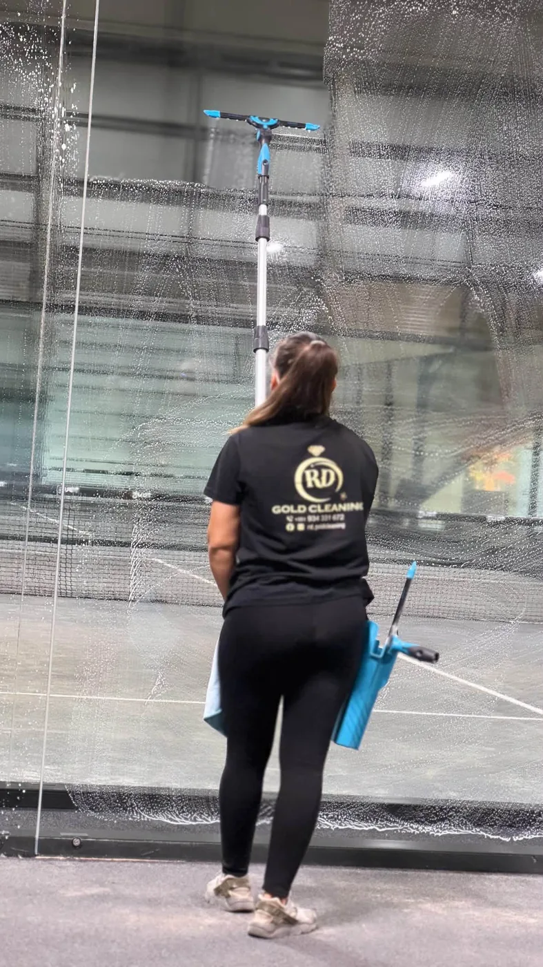 Profissional da Gold Cleaning a lavar uma parede de vidro num pavilhão desportivo